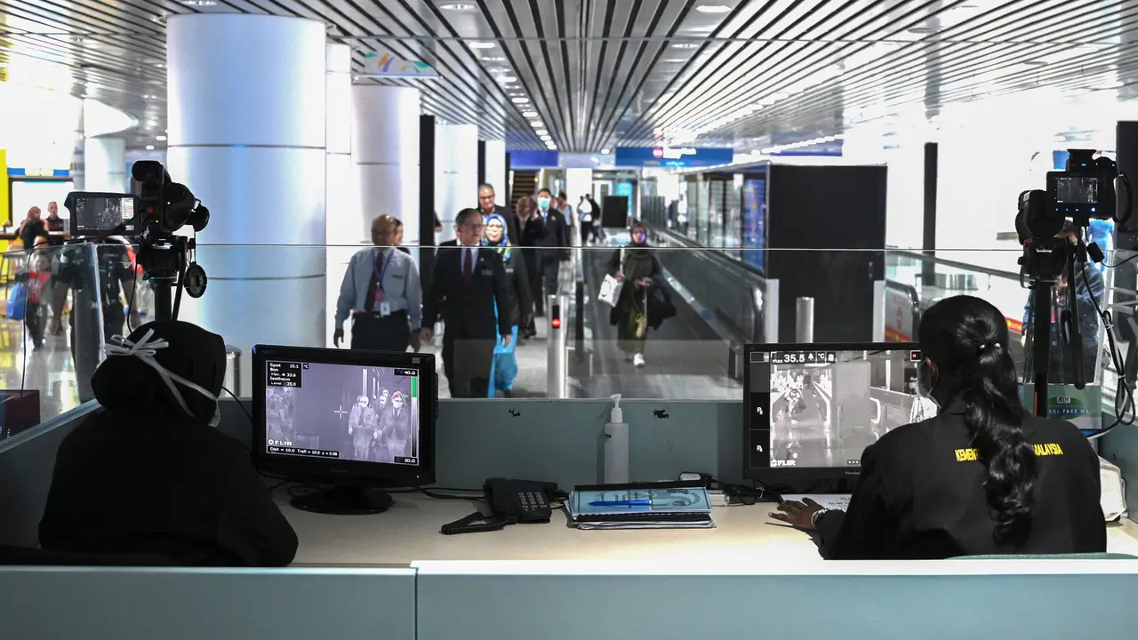 Petugas kesehatan memeriksa 'thermal scanner' untuk mendeteksi suhu tubuh penumpang yang tiba di Bandara Internasional Kuala Lumpur pada Selasa (21/1/2020). Pemerintah Malaysia mulai mengoperasikan alat pemindai suhu tubuh merespons penyebaran virus korona yang kian masif di China.