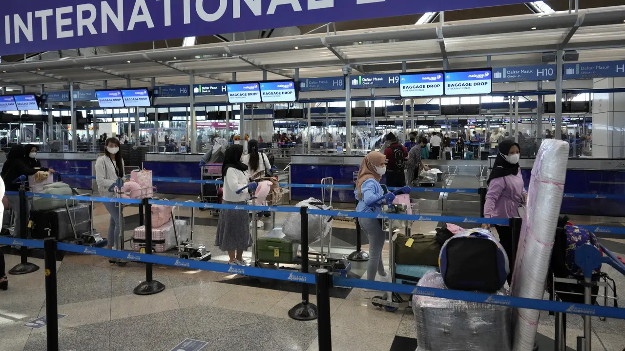 Pelancong mengantre di konter check-in Bandara Internasional Kuala Lumpur, Sepang, Malaysia, Jumat (1/4/2022). Mulai hari ini, Malaysia membuka perbatasannya untuk orang asing dan pelancong yang sudah divaksin COVID-19 lengkap tanpa harus menjalani karantina. (AP Photo/Vincent Thian)