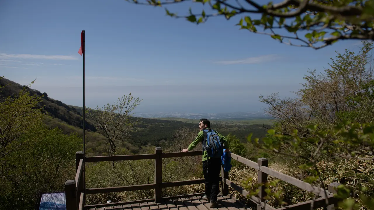 Seorang pejalan kaki menikmati pemandangan Hallasan, atau gunung Halla, di pulau Jeju, Korea Selatan (9/5/2019). Dalam catatan sejarah, Jeju disebut dalam berbagai nama, mulai dari Doi, Dongyeongju, Juho, Tammora, Seomna, Tangna atau Tamra. (AFP Photo/Ed Jones)
