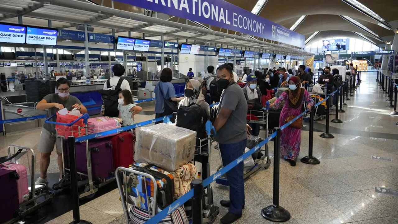 Pelancong mengantre di konter check-in Bandara Internasional Kuala Lumpur, Sepang, Malaysia, Jumat (1/4/2022). Mulai hari ini, Malaysia membuka perbatasannya untuk orang asing dan pelancong yang sudah divaksin COVID-19 lengkap tanpa harus menjalani karantina. (AP Photo/Vincent Thian)